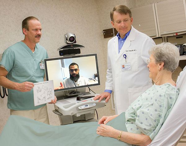 TeleStroke web team at CentraCare speaking with a patient in a hospital bed