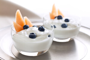 Two bowls of yogurt with fruit inside.