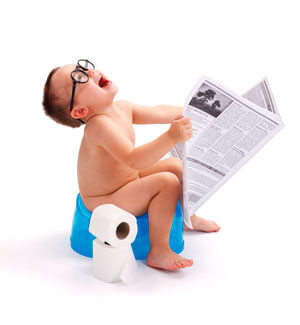 Toddler sitting on a training potty holding a newspaper and wearing glasses.