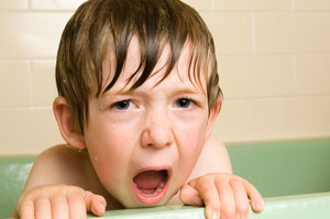 Young boy with wet brown hair in a bath tub.