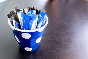 Small cup with different types of sugar packets in it.