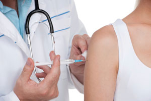 Medical provider injecting patient with syringe in upper arm