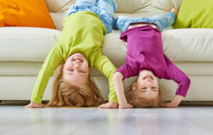 Two children hanging upside down off a couch.