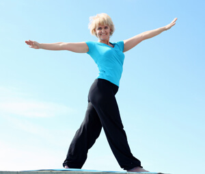 Woman in a blue shirt and black pants stretching out her arms.