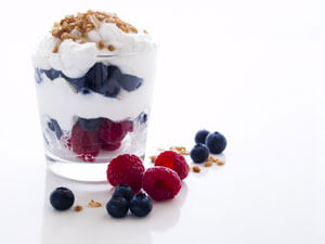 Clear cup of yogurt with fruit and granola.
