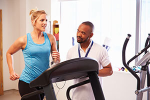 woman running on treadmill with coach next to her