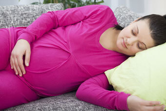 Pregnant woman lying on her side, holding her belly.