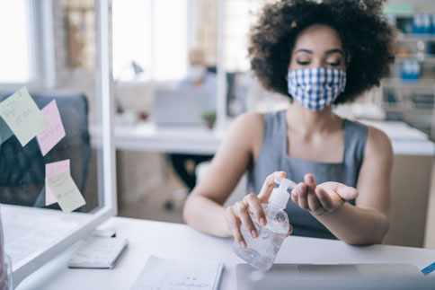 Woman wearing mask using hand sanitizer
