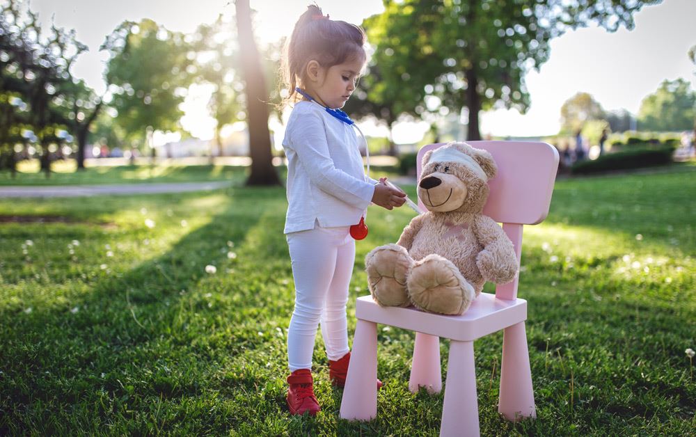 Little girl giving shot to teddy bear