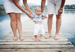 couple standing on dock with their baby