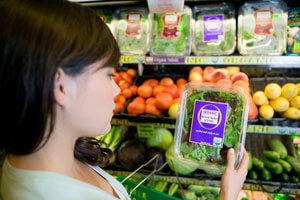 woman in grocery store looking at spinach