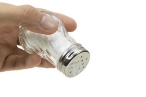 Hand holding a salt shaker.