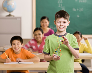 Child standing up in class showing a DNA strand.