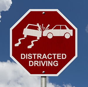 road sign that shows cars crashing and says "distracted driving"