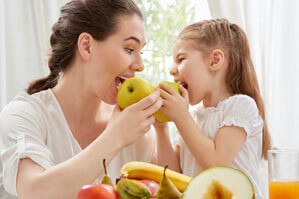 Woman and young child eating fruit together.