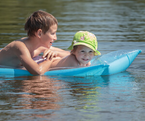 Two kids playing on a water raft.