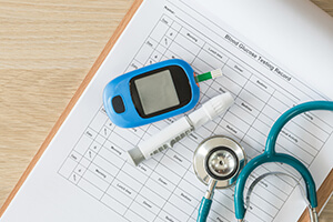 stethoscope and blood sugar meter on medical chart