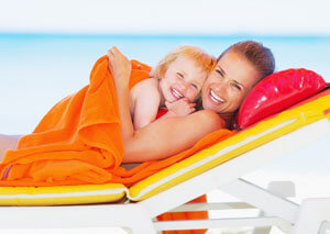 Woman and young child laying on a beach chair.