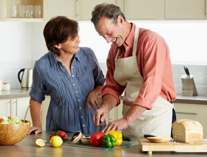 Man and woman cutting vegetables in a kitchen.