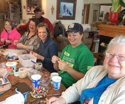 Kay Sime and faith community friends making prayer bead necklaces using Pass it on Crosses.
